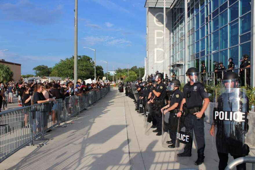 Police in riot gear guarding the Orlando Police Department headquarters as protesters look on, Sunday May 31st. Photo: Matthew Peddie, WMFE