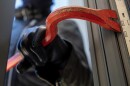 Thief holding a crowbar to break a glass window