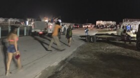 Fyre Festival attendees walk around the event site on Thursday night in Grand Exuma, Bahamas. Festivalgoers had paid thousands of dollars for villas and lodges on the beach, but instead found a chaotic tent city.