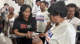 This photo taken with a smartphone shows Democratic gubernatorial candidate Keisha Lance Bottoms signing a campaign sign for a supporter during an Atlanta-North Georgia Labor Council (AFL-CIO) Labor Day lunch in Hapeville, Ga., Monday, Sept. 7, 2026. (AP Photo/Bill Barrow)