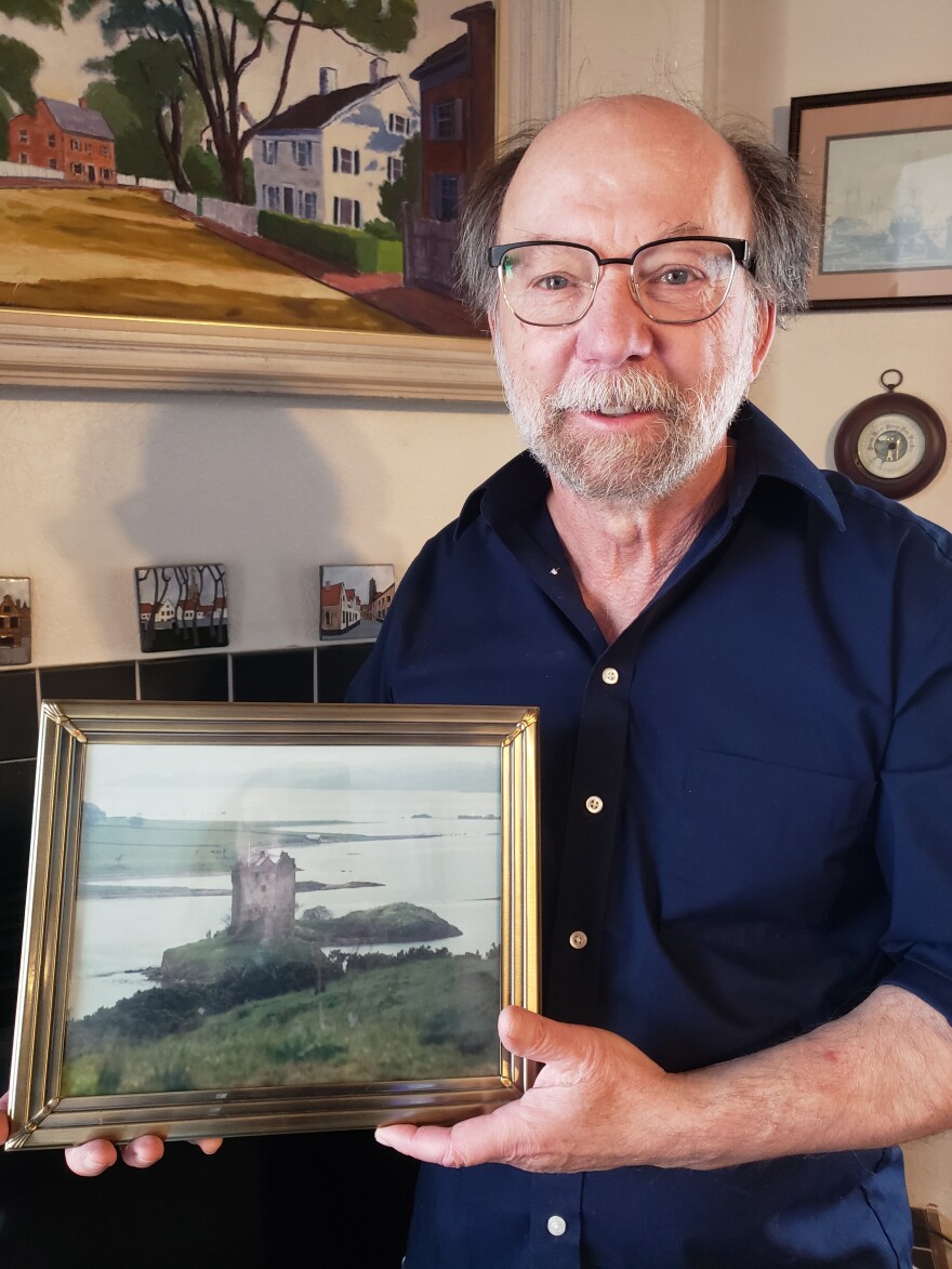 A man holding a framed photo of a castle