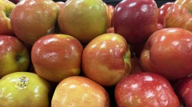 Rows of red apples sit stacked on top of each other at a grocery store.
