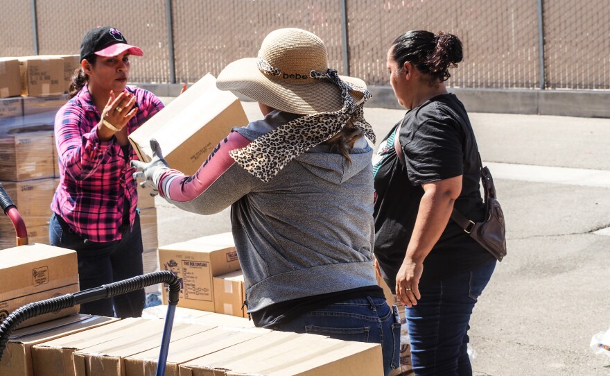 Volunteers and paid staff unload boxes of cheese, bread and rice for needy people in Heber, many of them elderly.