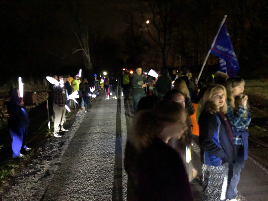 Protestors gather with flags and light-sticks on the road outside of Gov. DeWine's home