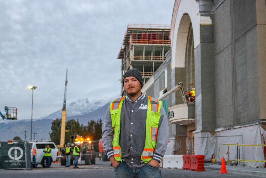 A man in a yellow safety vest in front of a construction site.