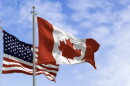 Canada and american national flags waving in the wind on a clear day. 