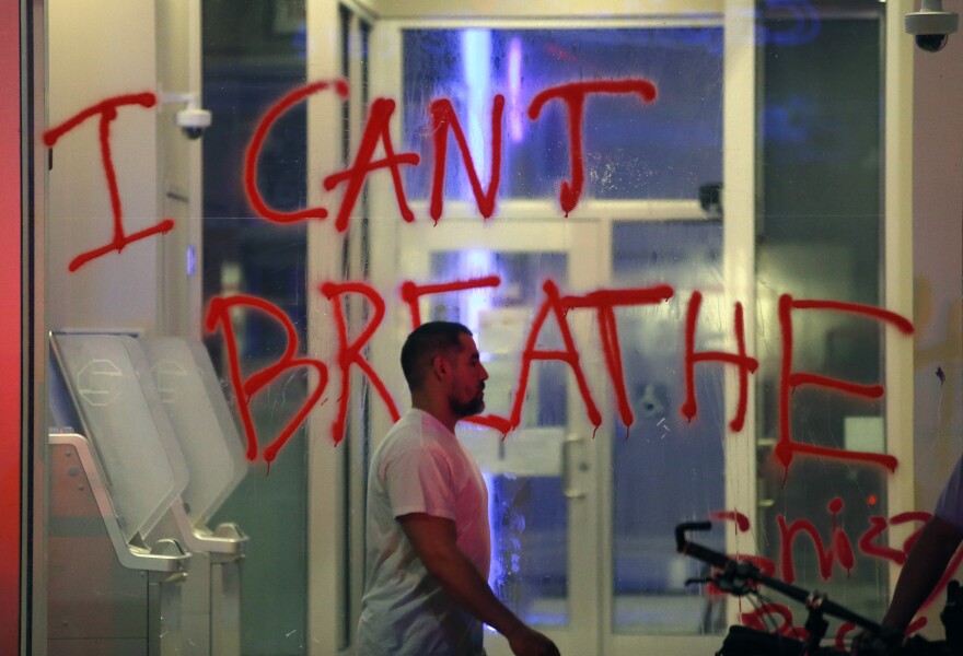 A man walks past a vandalized business during the Justice for George Floyd protest in Philadelphia on Saturday night.