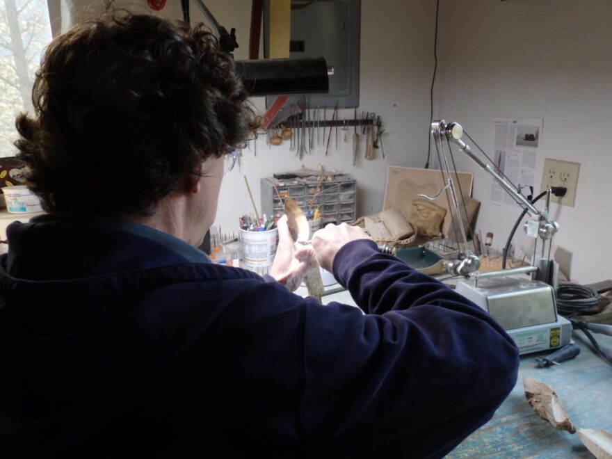 Bruce Schindler carves a piece of mammoth ivory using a dental tool. (Abbey Collins)