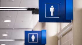 A vivid blue mens restroom sign with the female sign in the background.