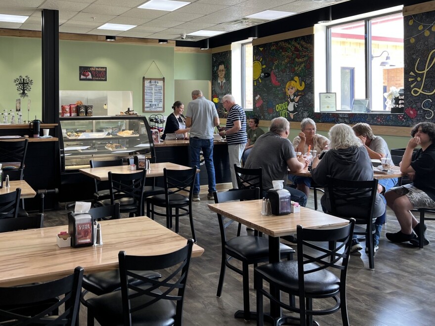Patrons sit at tables and order food at a cafe and coffee shop.