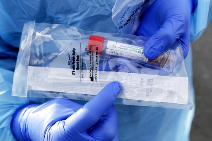 A health worker displays the packaged nasopharyngeal swab, which goes about two inches into the nasal cavity, used on patients at a drive-thru COVID-19 testing station for University of Washington Medicine patients Tuesday, March 17, 2020, in Seattle. The appointment-only drive-thru clinic began a day earlier. Health authorities in Washington reported more COVID-19 deaths in the state that has been hardest hit by the outbreak.