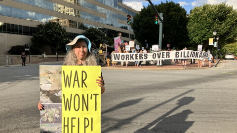 Demonstrator Lola La Fey holds a sign showing damage her home sustained from Hurricane Helene as she stands near Pack Square in Asheville on Friday, August 28, 2026.