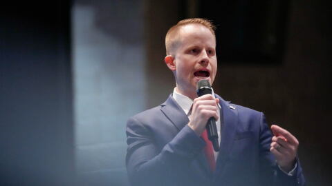 A man in a suit speaks into a microphone.