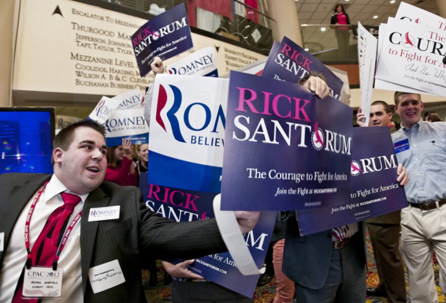 Supporters of Rick Santorum and Mitt Romney vie for attention at CPAC in Washington, Saturday, Feb. 11, 2012. 