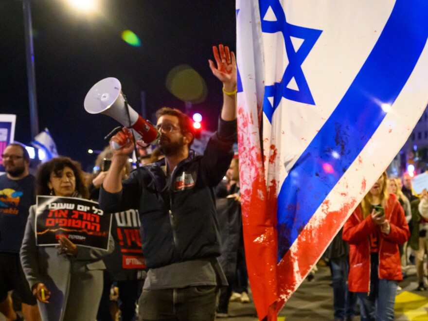 A protester with red paint on his hand marches through the streets after demonstrating outside the Israel Defense Forces headquarters on Friday in Tel Aviv, Israel. Earlier, the IDF had said its forces accidentally killed three hostages being held in Gaza when it mistakenly identified them as potential threats.