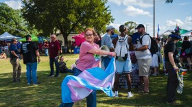 Holly Land dances with a trans pride flag to distract from protesters at Out on the Brazos on Oct. 18, 2025.
