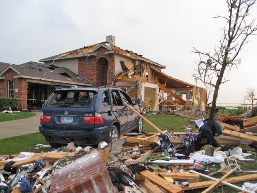 A SUV sits next to a damaged home in Forney.