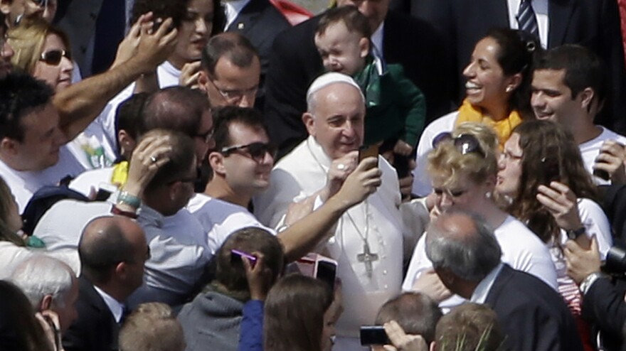 Pope Francis poses for pictures with the audience after Palm Sunday service in St. Peter's Square at the Vatican Sunday.