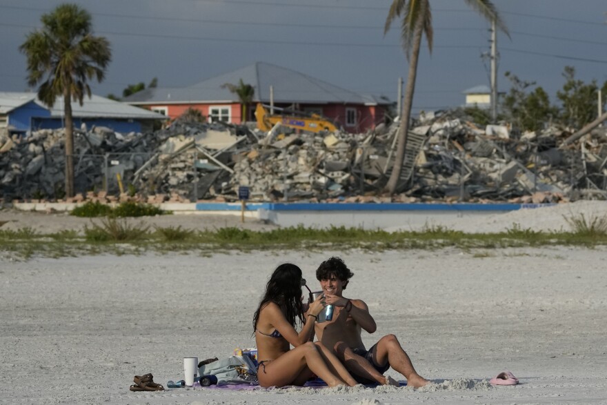 Two people toast a drink on the beach. 