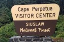 A brown National Forest sign reads "Cape Perpetua Visitor Center"