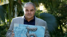 Xavier Cortada is Miami-Dade County’s first artist in residence. He is holding a yard sign from his project "The Underwater."