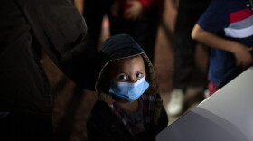 FILE - An unaccompanied minor looks up as he waits to answer questions from a U.S. Border Patrol agent at an intake site after he was smuggled on an inflatable raft across the Rio Grande River, March 24, 2021, in Roma, Texas.