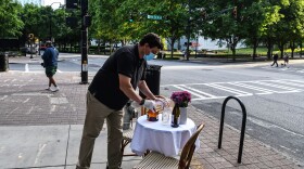 A man decorates a bistro table outside his restaurant amid the coronavirus pandemic in Atlanta on April 27. As states reopen, some are allowing restaurants to add outdoor seating in streets and parking lots.