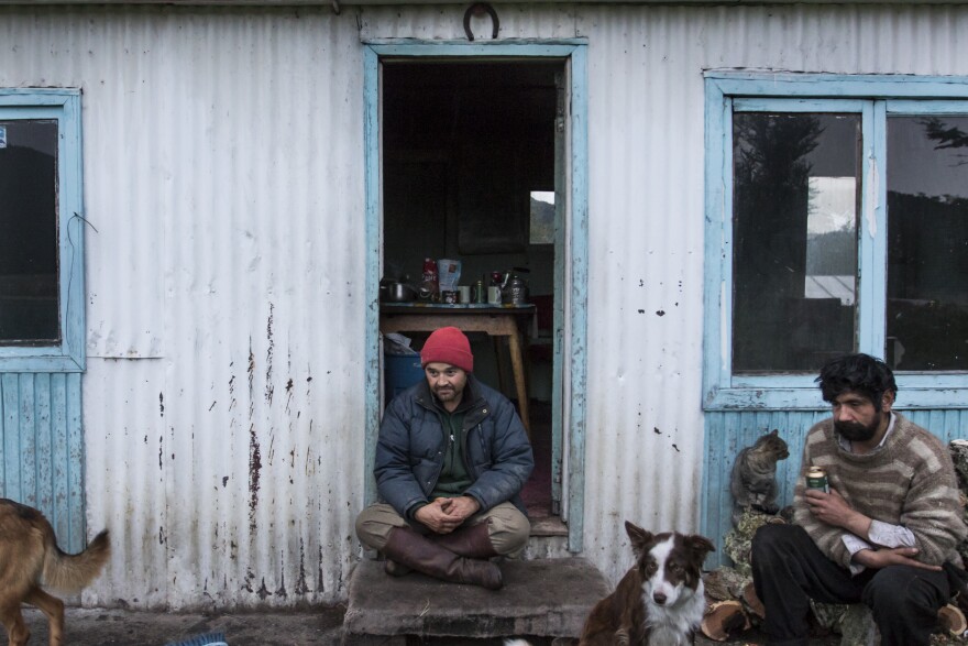 Outside the ranch kitchen, Juan Luis and work companion Luis Enrique (right) rest after hauling firewood.