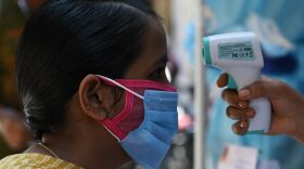 A health worker checks the body temperature of a woman as a preventive measure against the Covid-19 coronavirus at residential area in Chennai.