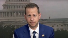 A man in a blue suits looks at the camera
