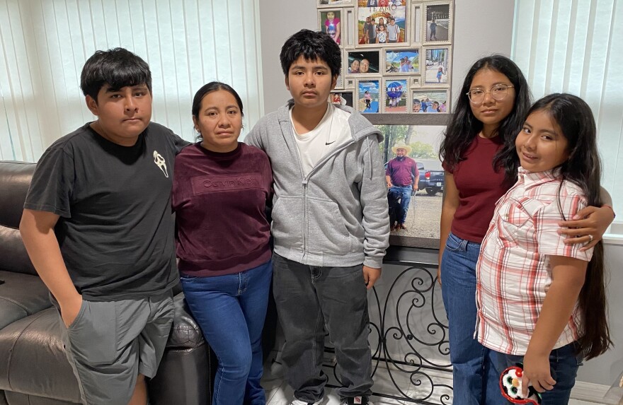 The Juarez children and their mother pose for a portrait in front of a photo of their father, Esvin Juarez, at the family's home in Apopka on Tuesday. From left to right, they are Cesar Juarez, 15, Rosemari Miranda, Josue Juarez, 13, Beverly Juarez, 21, and Valery Juarez, 9.