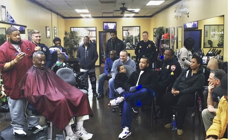 Many people gathered at Headliners Barbershop, while one person cuts hair.