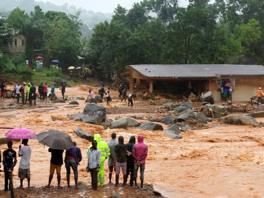 Floodwaters rage past a damaged building in Freetown, Sierra Leone, on Monday.