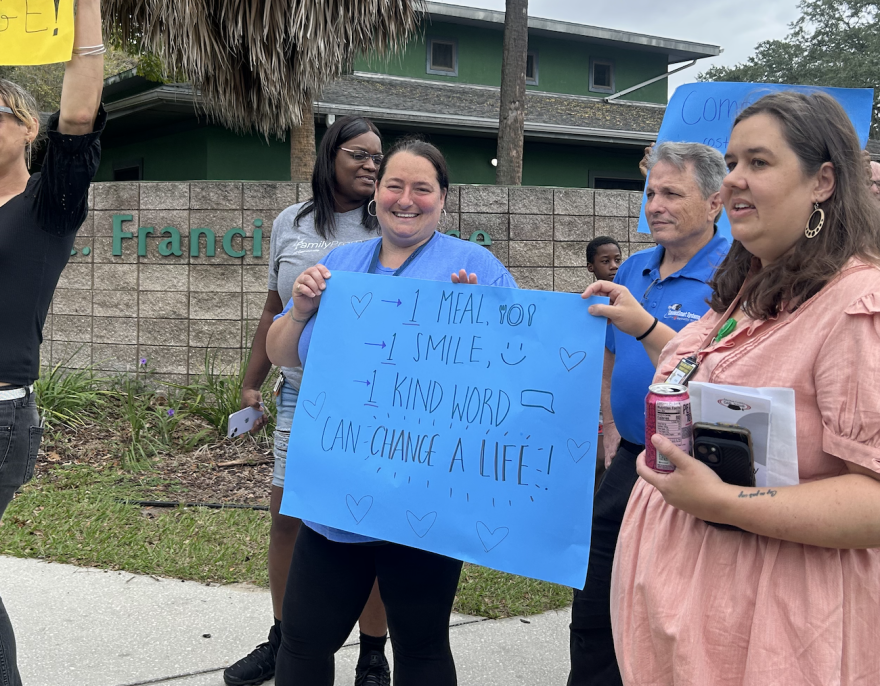 A volunteer holds up a poster reading “1 meal, 1 smile, 1 kind word can change a life” during St. Francis House’s World Homeless Day event on Oct. 10.