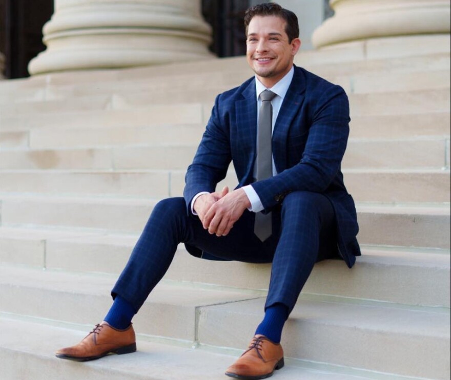 A man in a blue suit sits on steps to a legislative building