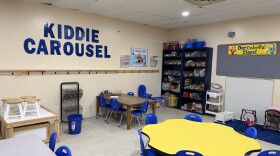 An empty childcare center classroom with "Kiddie Carousel" in big, blue letters on the wall