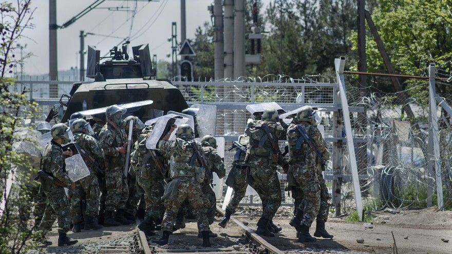 Macedonian police react as migrants and refugees throw stones during clashes at the border Sunday.