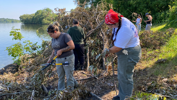From left, Kaniehtine LaFrance and Ronni Sunday prune branches of a white willow tree along the shore of the St. Lawrence River.
