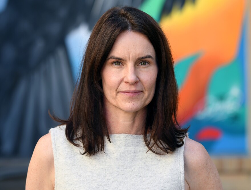 A portrait of Julie Hoebel, who is wearing a white sleeveless shirt.