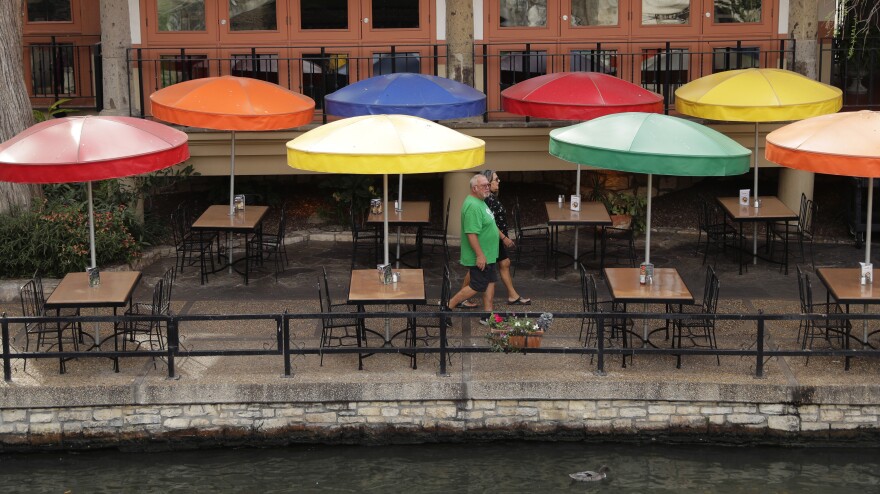 Visitors walk past a restaurant on the River Walk Monday in San Antonio.