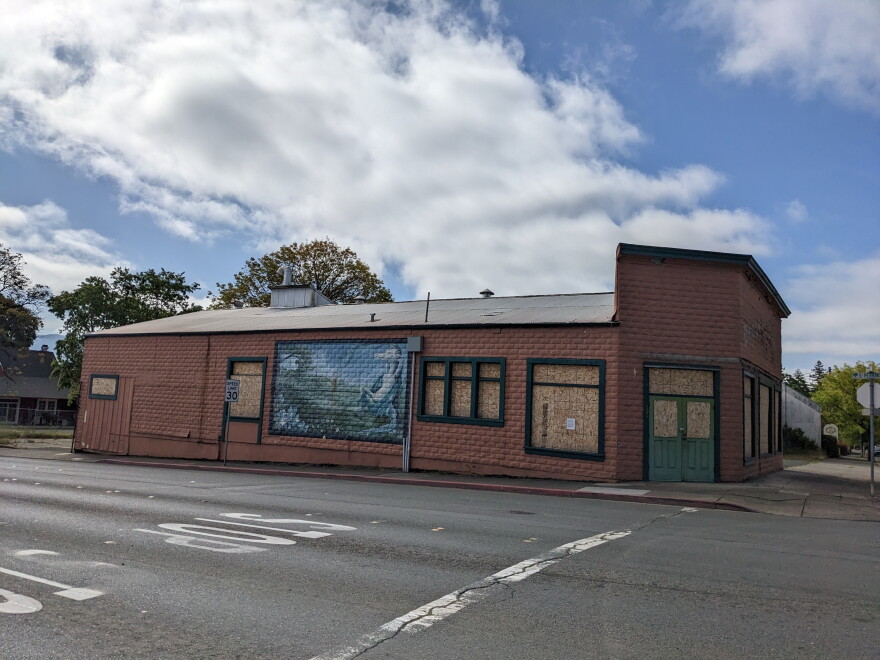A large metal-sided shed with a faded mural and boarded-up windows.