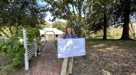 SmartShare Housing Solutions Executive Director Anne Wyatt stands on the property while holding the development plan.