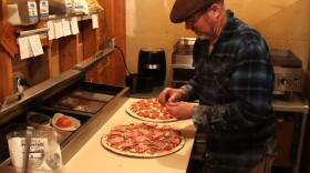 a man puts pepperoni on a pizza