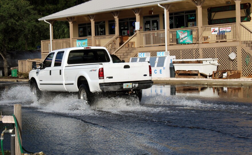 Cars drive through at least two feet of rain to make it to the Cedar Key General Store on Friday for ice and other necessities. (Briana Erickson/WUFT News)