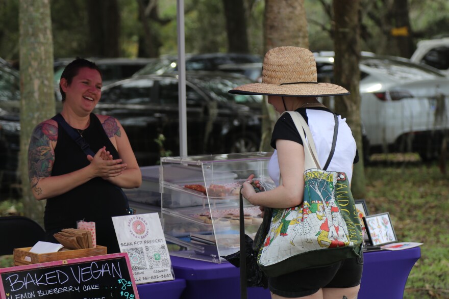 Brie-Anne Ezratty, 31, owner of Baked Vegan, greets customer Makayla Rutski, 23, at the farmers market at Critter Creek Sanctuary, Gainesville, Florida, Sunday, Feb. 11, 2024. (Nicole Beltran/WUFT News)