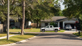 View of houses with a truck on the side of the road and a car in the driveway