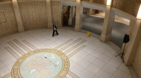 A pedestrian traverses the rotunda in the New Mexico state Capitol building in Santa Fe, N.M., on Thursday, March 16, 2023, as legislators debated late into the evening inside House and Senate chambers. (AP Photo/Morgan Lee)