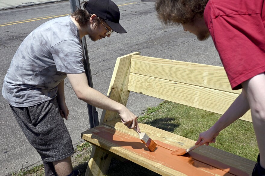 Luis Lage (left) who helps run a mass transit and cyclist advocacy Instagram page called Car Free BPT, and Liam Conway painting the new bench located by Bridgeport Hospital on 7/12/25. Lage estimates around five percent of all bus stops in the city have shelter or seating.