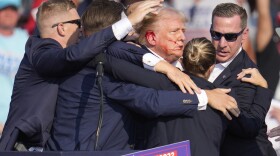 Republican presidential candidate former President Donald Trump is surrounded by U.S. Secret Service agents as he is helped off the stage at a campaign rally in Butler, Pa., Saturday, July 13, 2024.