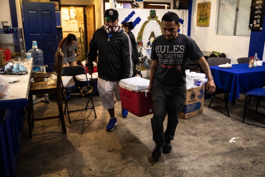 Friends come help the restaurant load coolers filled with stew onto a truck. Customers, employees and the owners, all of whom are Honduran, volunteer their time to help feed the thousands of migrants.